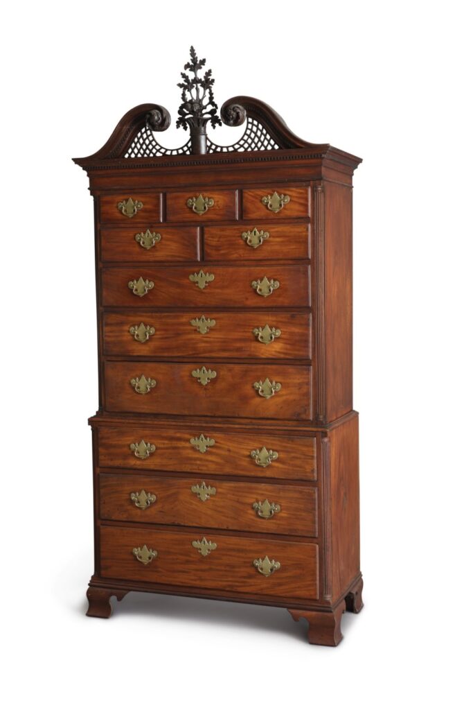 a mahogany chest-on-chest from philadelphia, with original brass hardware, intricate carved ornament on top, and a solid provenance, being sold at sotheby's