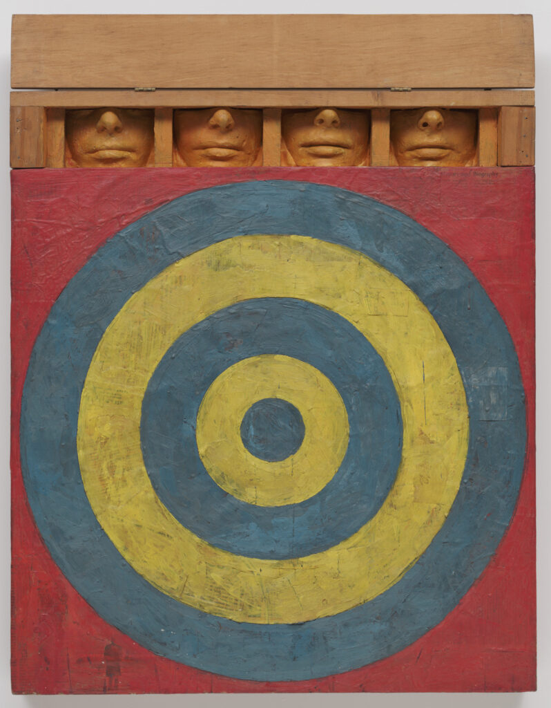 jasper johns painting target with four faces from 1955, four alternating bands of yellow and blue around a blue circle forming a target on a square canvas with the corners slash background in red. on top is a wooden construction like a frieze, with a single piece of wood hinged at the top to open or close, revealing four identical cast plaster models of the lower half of someone's face, from the bridge of the nose to the middle of the chin, lips closed, and all painted a unifying pale orange that kind of blends into the finish of the lumber. collection moma