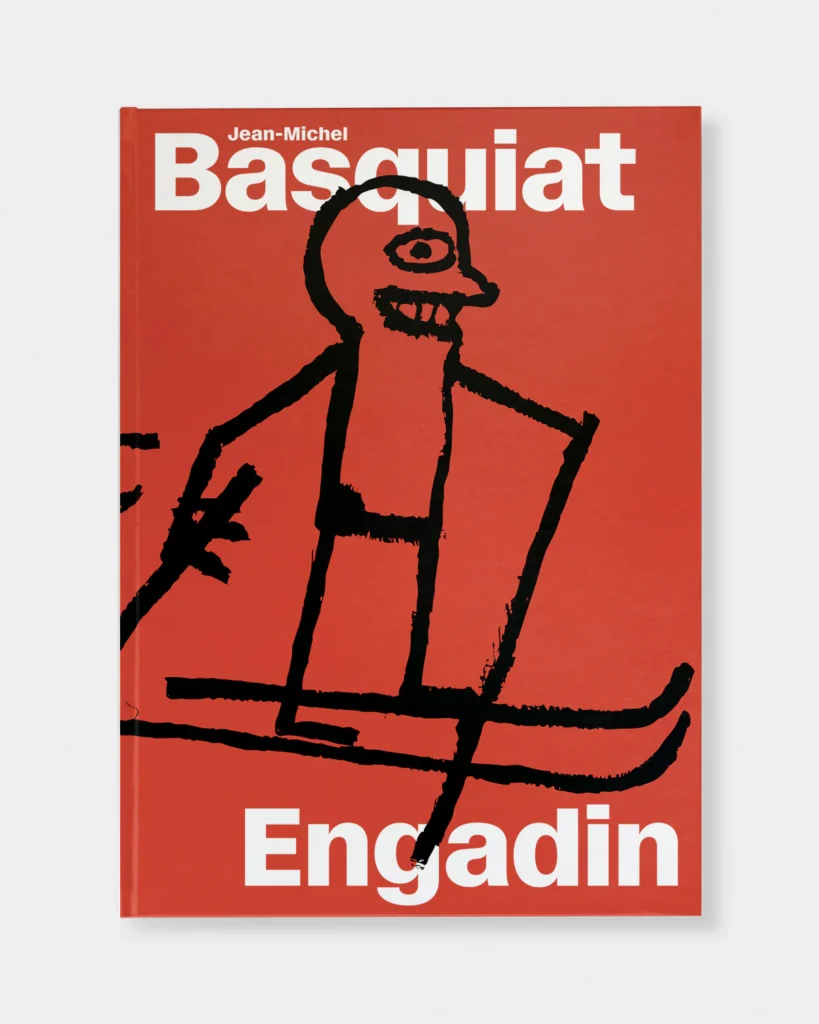 a black painted stick figure of a skier in profile with a rectangular body and a cyclopic eye over a toothy grin on a red background fills the cover the jean-michel basquiat engadin exhibition cover, overlapping slightly with the show/book title, printed in a sans-serif white, from the exhibition in st moritz by hauser & wirth gallery.