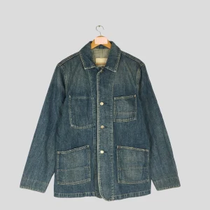 a thumbnail image of a blue denim work coat by smith's american, with four patch pockets and steel buttons, from google image search, which says it was once on etsy, but the etsy link to it is a completely different coat, and etsy's own search is somehow even worse than google, and there's no archive, so who knows. but it is very close to megan craig's de kooning coat, which she didn't know the make of.