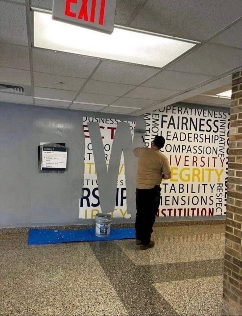 toothlessly captioned new york times photo posted to the nazi social media platform x by nyt reporter adam goldman of a government employee painting over the fbi core values word cloud mural at quantico with battleship gray paint roller. the stroke forms a large W that allows words like respect, initiative, leadership, integrity, seriousness, diversity, intergrity, and constitution to be read before being obliterated.