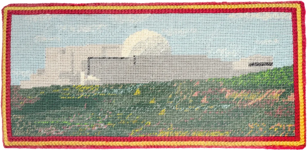 a needlepoint kneeler created by vicky cropped of the united kingdom depicts a fairly naturalistic (for a needlepoint) image of the sizewell nuclear plant, with its distinctive white geodesic dome and white rectangular buildings, set in a slightly idealized green meadow flecked with flowers. the whole thing's ringed by a red and yellow border, via the world of interiors, but it's from someone's book who worried that the death of queen elizabeth was going to wipe out the tradition of needlepointing kneelers, and the world of interiors said, sure, we haven't been to a church in forty years but we'll run with that