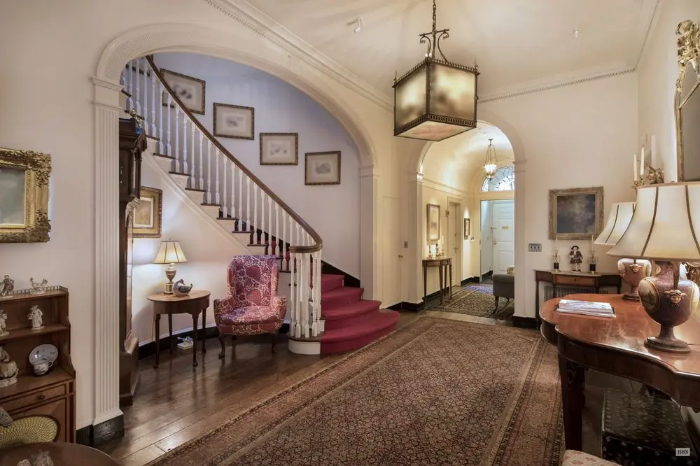 the rockefellers entry hallway and foyer where the curved staircase is set in an arched niche, but the parquet floor has some carpet on it, and the furniture is american antique because the house is colonial revival, like the rockefellers themselves i guess, but this is where the manet vase of lilacs was hanging, on the right, though it's been replaced here by a redon which is blurred out in this real estate listing, both were clearly presented at christies