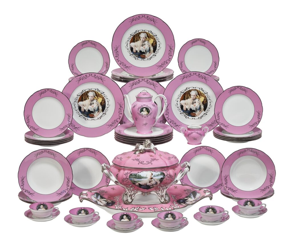 a three tiered display of a pink and white limoges porcelain dinner service and tea service, plus a pink soup tureen and platter, all by cindy sherman, but only some—the tureen and platter, the interior of the tea cups, the tea pot, and the presentation plates—with screenprinted photos of sherman as mme pompadour. via christies feb 2025