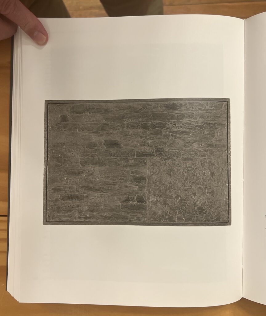 a photo of a page from the jasper johns catalogue raisonne of a grey sculp-metal on canvas painting of a us flag, p88, from 1960, originally made as a gift to robert rauschenberg, but the photo is rotated 180 degrees to become a study for a repetition of an upside-down johns flag