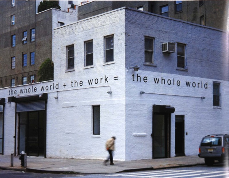 the brick industrial garage on the corner in the west village that was gavin brown's enterprise is painted white, and martin creed's work no. 300, the whole world + the work = the whole world, is painted in lower case, sans serif font along the top of the first floor, like frieze. a blurry figure is walking on the sidewalk in front of the bulding.