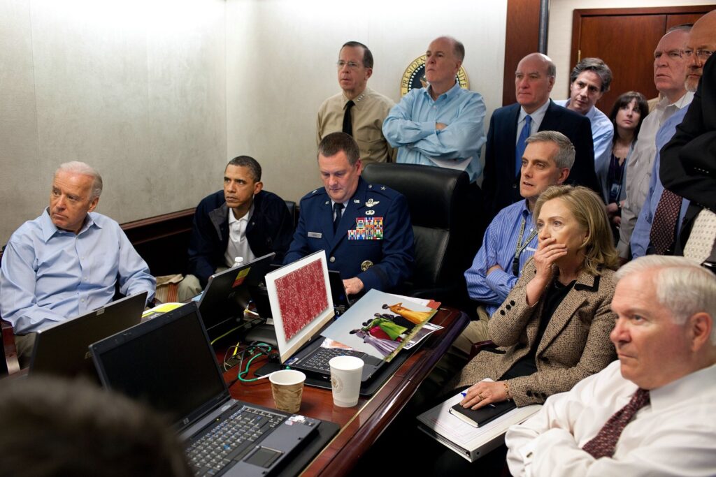 the situation room at the white house in which obama and a younger and alert joe biden (sigh) sit across from hilary clinton and a bunch of other ppl all staring off camera to the left, as they watch on a monitor out of the image as their art advisor facetimes in from frieze la art fair, reporting on the condition, suitability, and availability of various paintings. in front of hilary, exposed to the camera, are images of the tyler mitchell preview pdf she got from gagosian, and the rashid johnson preview pdf on her computer screen that iwan wirth sent over for her consideration, is the concept here. they were actually, i believe, watching seal team six take out osama bin laden. i don't know of any images of peak drone strike obama