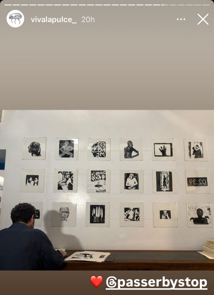 screenshot of viva la pulce's instagram story of an installation photo of the gallery, with a white wall filled by a three row grid of book-sized black on white woodblock prints, and a white guy with dark hair, facing the wall at a ledge/desk. they're by gavin brown