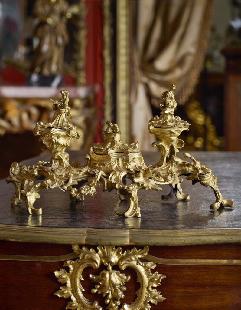 a bonkers 18th century gilt bronze inkwell in the most over the top rocaille style in its natural habitat, on an 18th century french desk similarly encrusted with gilded decoration, and with a gold silk drapery in soft focus in the background. from christie's paris