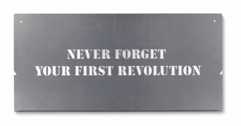 a metal stencil with the phrase never forget your first revolution punched out in all caps in the center, an edition by tania bruguera from 2005 titled terror chic, published by editions schellmann