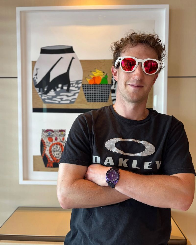 mark zuckerberg confirming the nerd-to-misogynist fascist pipeline posing in a pair of surveillance oakleys and an oakley t-shirt, with his arms folded, in front of a 2017 jonas wood print titled shelf still life, which depicts two shelves of painted ceramic pots by wood's wife shio kusaka including one with dinosaurs on it that wood has made large scale paintings of, which you'd think zuck would be able to afford, but I guess he needs to surveil you more first. image: the verge, i think