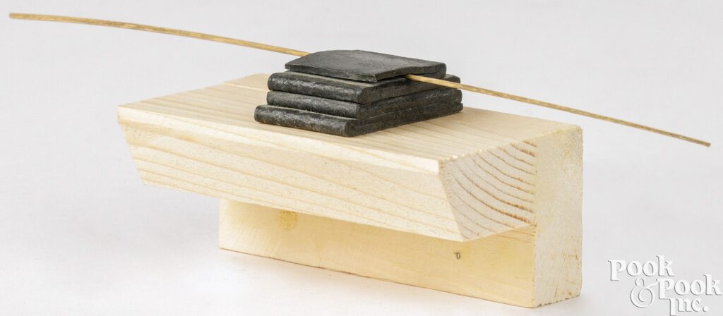 a one inch wide strip of lead folded back and forth upon itself into a gradually narrowing stack, with a long blade of pale grass pinched in place under the top fold, and protruding equally from either side like a single cat whisker, a beautiful and simple combination of weight, solid, even monumentality, and light, nature, floating, permanence and fleeting. sitting on a stupid unpainted wood bracket like a pedestal, a sculpture by bill walton, being dumped by albright college, and being liquidated and poorly presented by pook & pook, yet it remains a masterpiece.