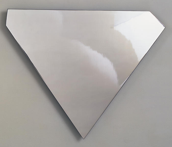 ellsworth kelly's untitled wall relief in polished stainless steel is in the asymmetrical shape of a superman logo-like shield, a downward pointing triangle with the top corners cut off unevenly. it's photographed against a plain grey background, and shows light and shadow reflecting across the upper right corner. via gemini nga