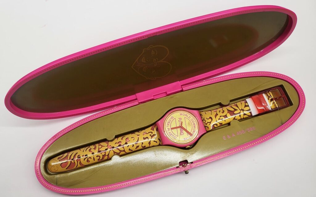a pink bodied swatch with gold face and gold filigree decoration on a pink band sits in an elongated gold-lined pink case. futuring is a limited edition swatch created in 2015 by eva and adele. this image came from an ebay seller