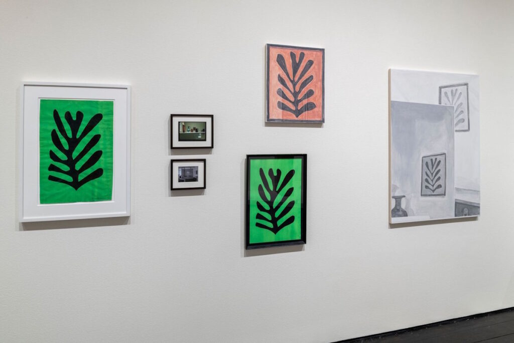 a white wall at the menil collection in houston has several artworks related to matisse cutouts of a palm frond. from left, a black on green original matisse in a white frame; two snapshots of a red matisse cutout in the de menils' kitchen; a green matisse copy made for dominique by william steen under a desaturated red painting of a matisse cutout by francesca fuchs, and next to that, a larger painting by fuchs of what looks like two archival black and white photos of the matisse installed in the de menils' house, stacked on top of each other. very meta, via the menil