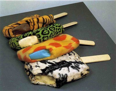 four good humor ice cream bar sculptures made of fake fur fabric in animal skin patterns, but garish colors, against a black background. by claes oldenburg
